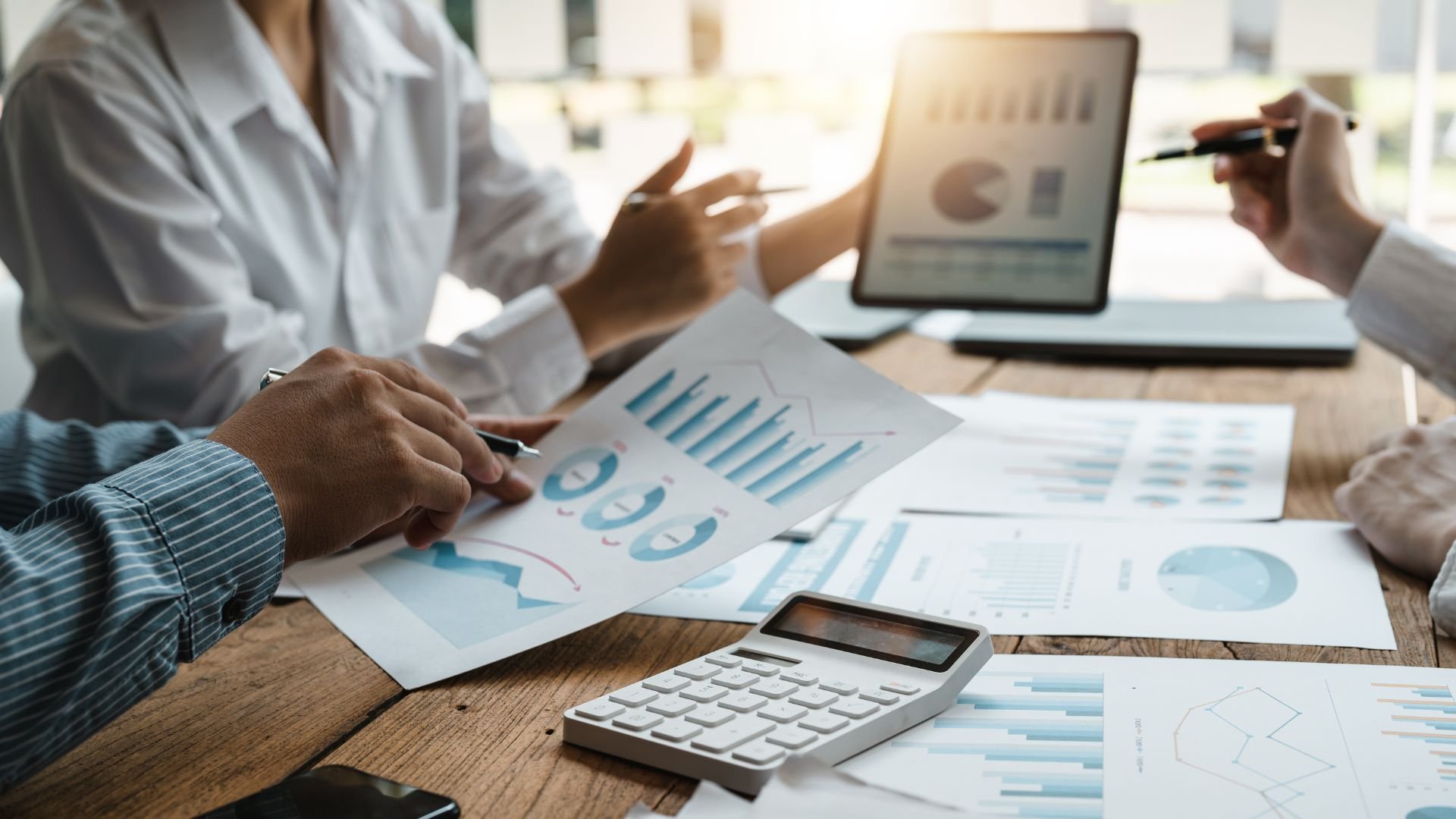 Business team analyzing financial graphs and data on laptop and papers